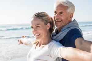 Glückliches Paar am Strand mit ausgebreiteten Armen, lachend und unbeschwert, durch Paarberatung Paartherapiehend, Liebe, Harmonie